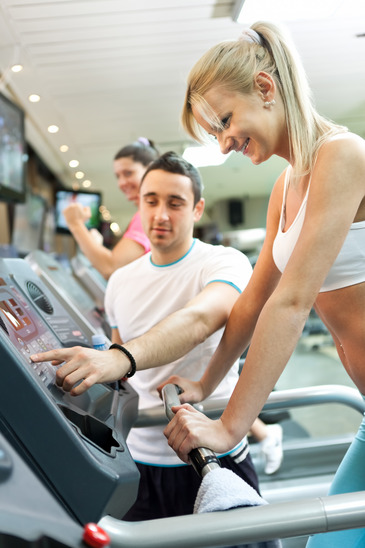 Personal Trainer Helping Woman Use A Treadmill