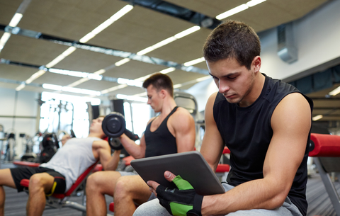 Man Recording Personal Bests On Tablet At The Gym